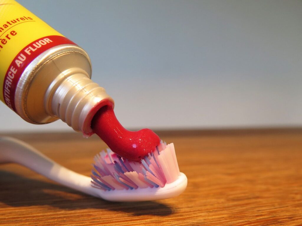 Zahnpasta wird aus der Tube auf eine Zahnbürste gedrückt.